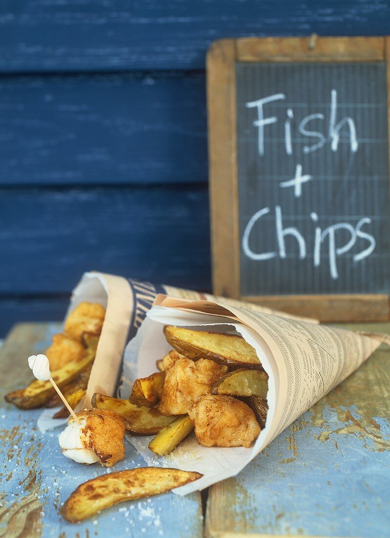 Fish & Chips in Zeitungstüten, dahinter Kreidetafel