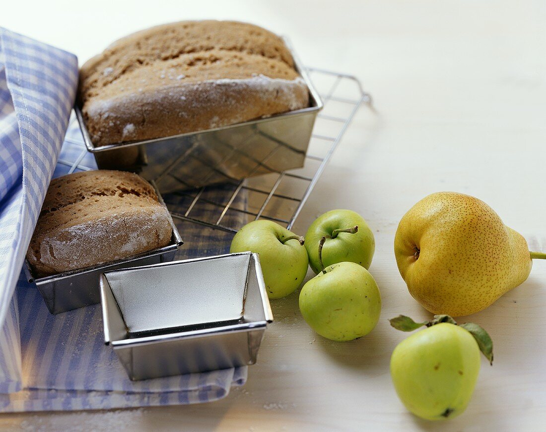 Two tin loaves, fresh apples and a pear