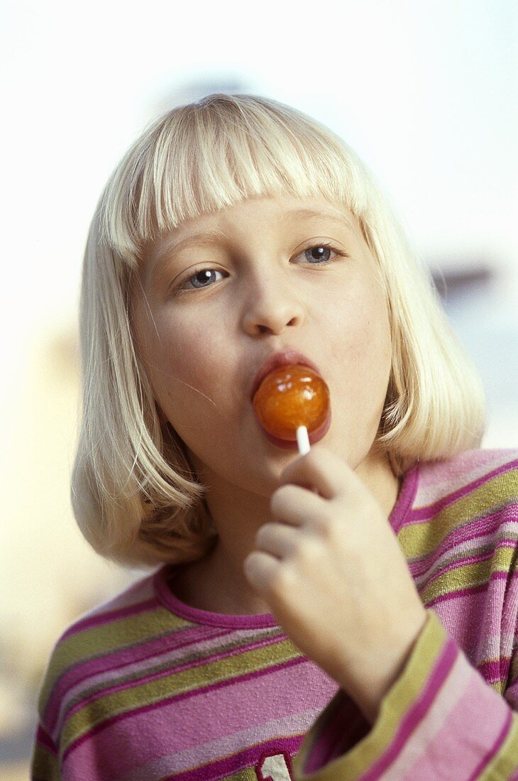 Blond girl sucking a lollipop