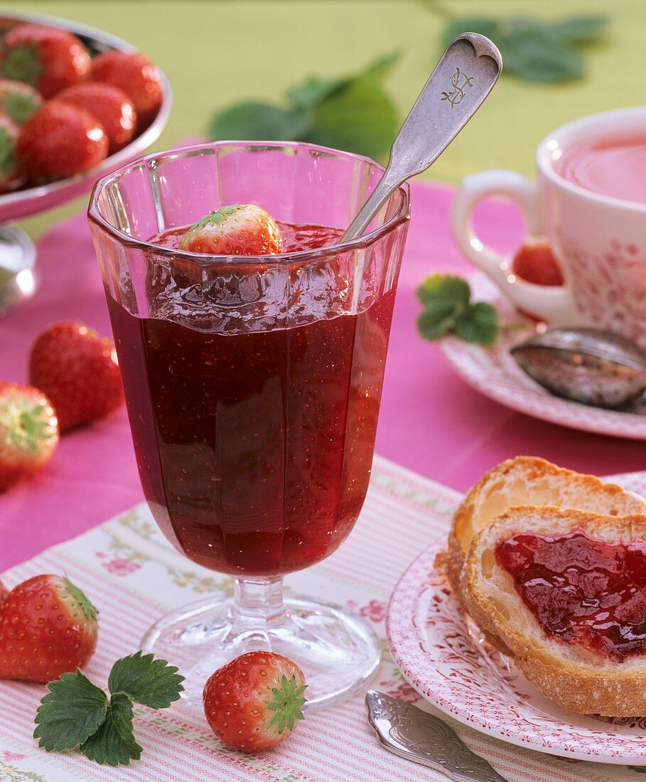 Strawberry jam in a glass and on a slice of bread