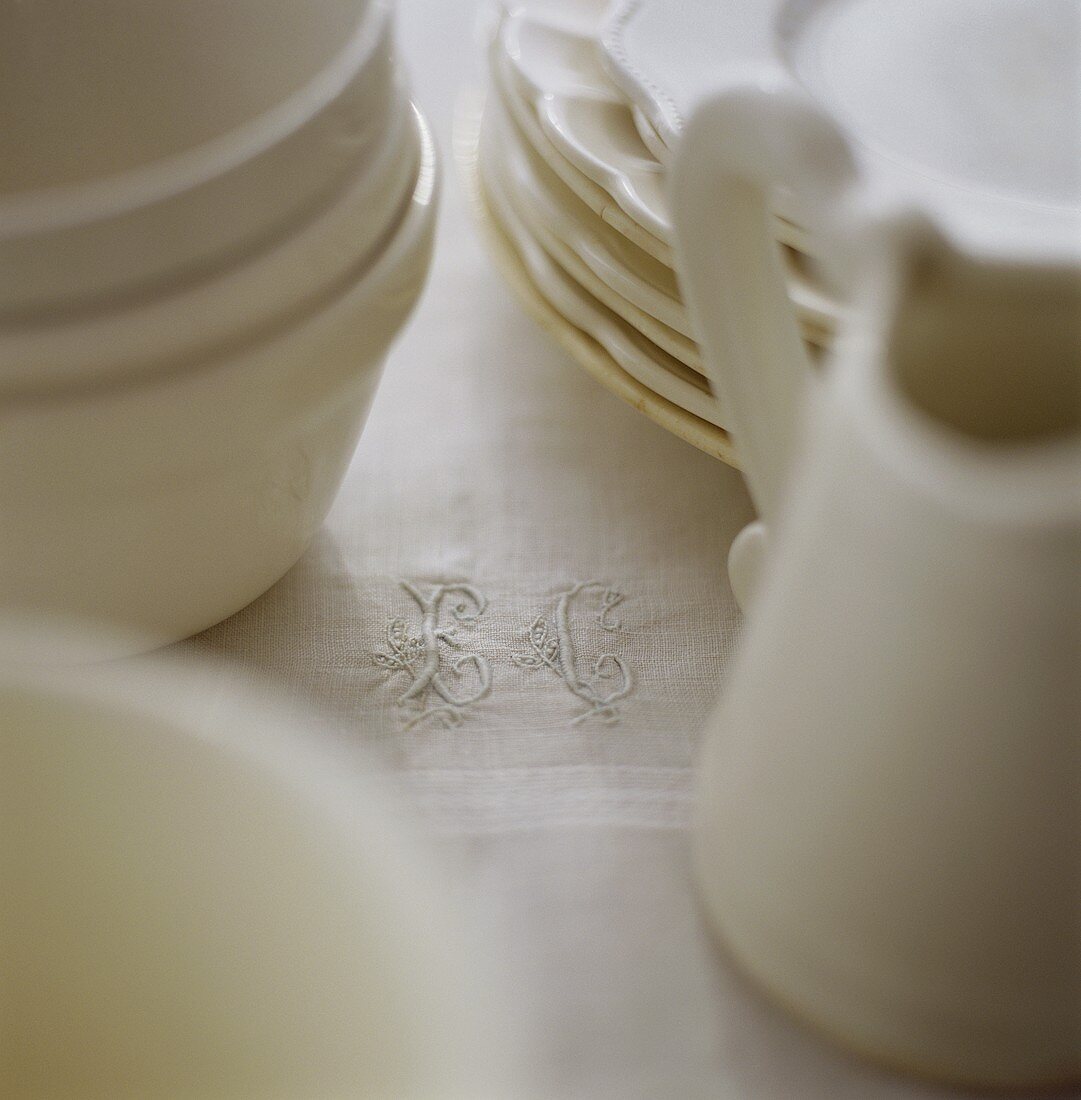 White crockery on tablecloth with embroidered initials