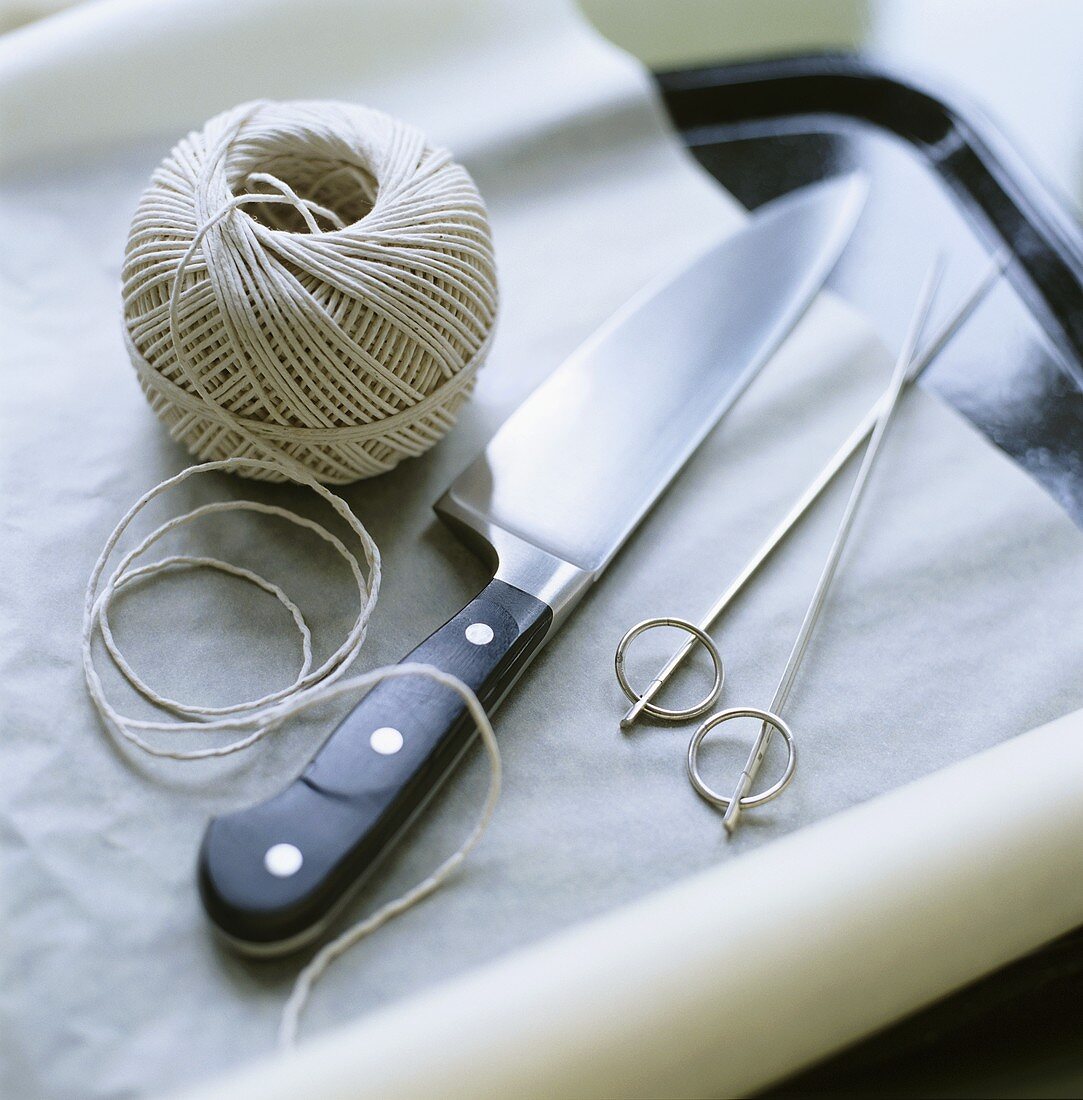 Kitchen utensils: ball of string, knife, skewers, baking parchment
