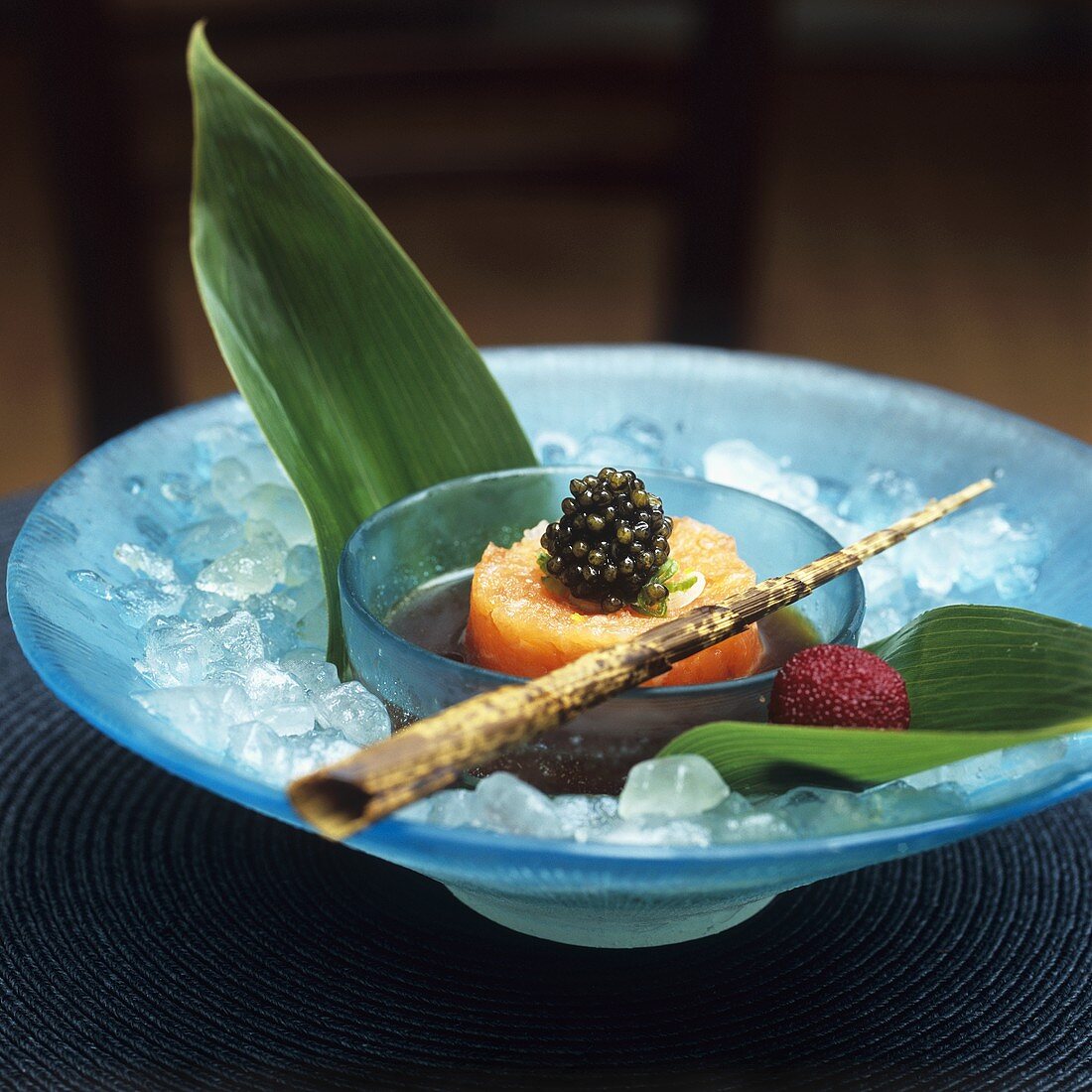 Salmon tartare with caviar in a small bowl, bamboo leaves