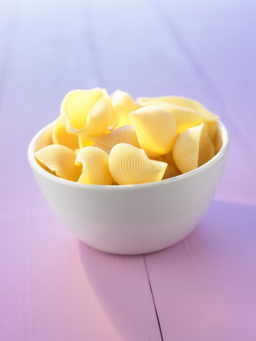 Raw pasta shells in a small bowl