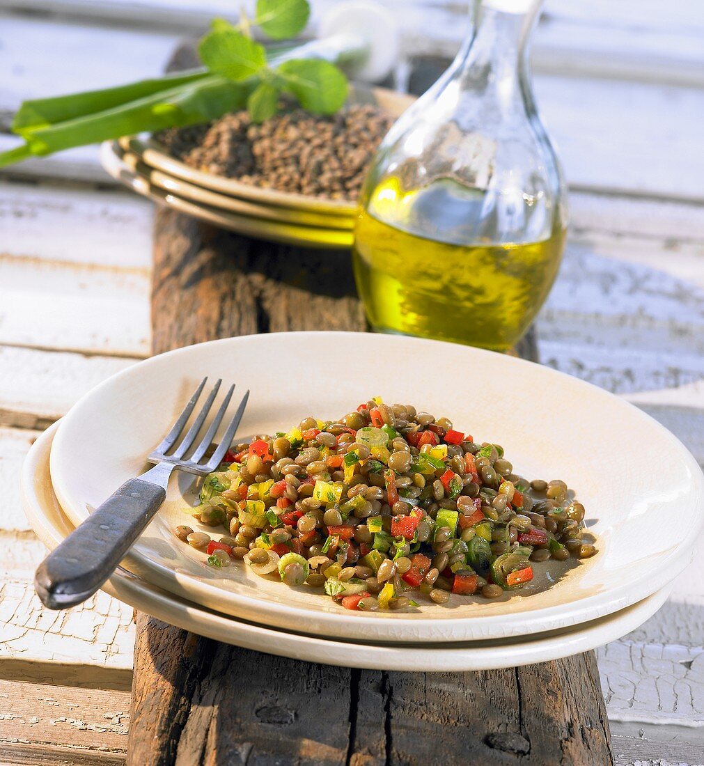 A large plate of lentil salad and a bottle of olive oil