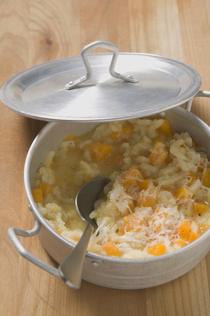 A pan of pumpkin risotto with propped pan lid