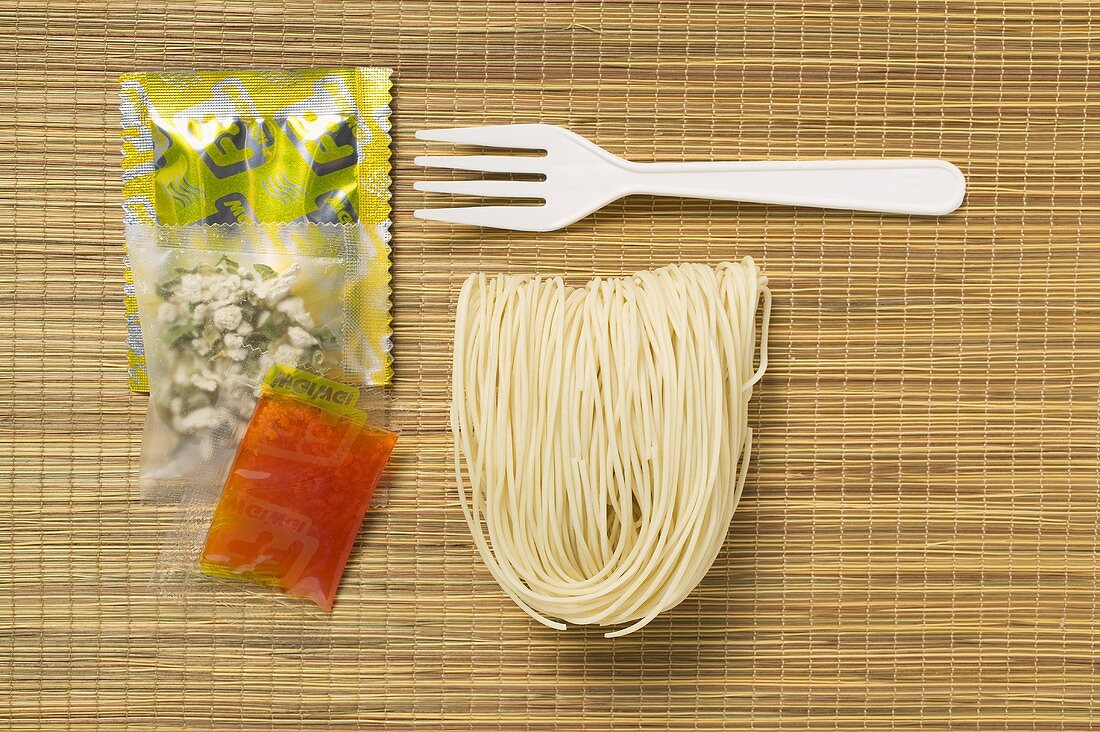 Asian instant noodles with spice mixture & fork on bamboo mat