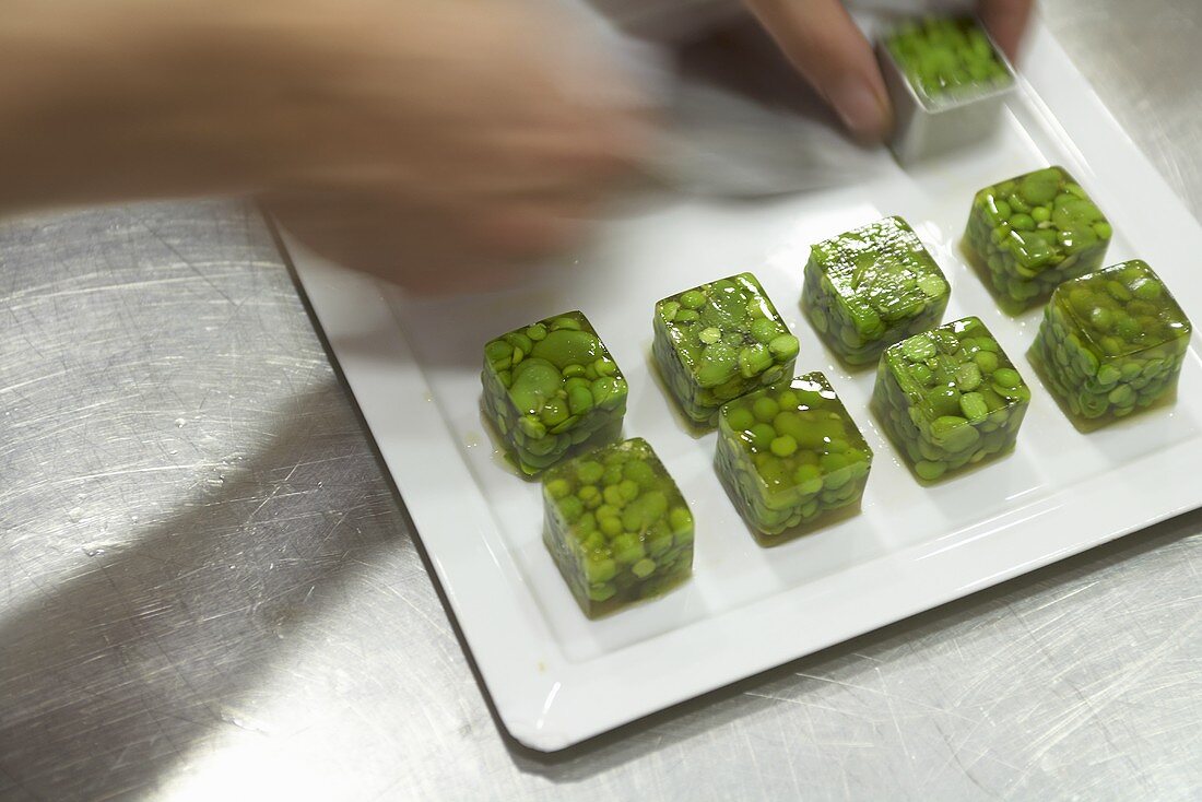 Putting cubes of jellied peas on a plate