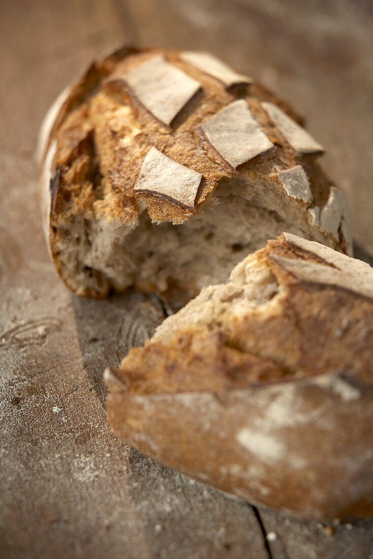 A broken loaf of rustic bread on wooden background