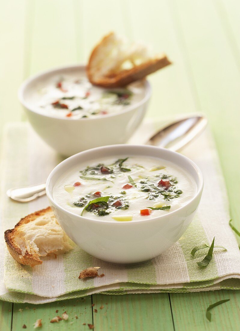 Two bowls of cream of kohlrabi soup with ramsons & white bread