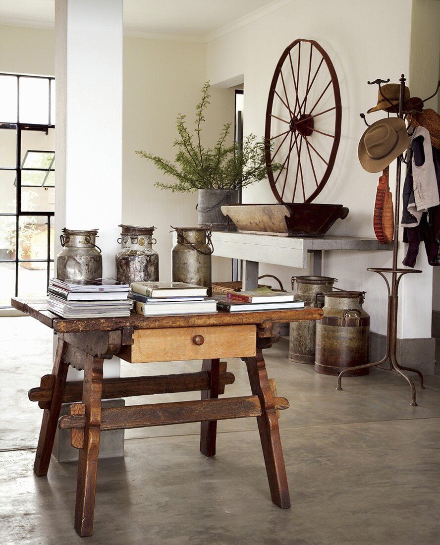 Rustikaler Holztisch mit Antiquitäten und Büchern in Wohnraum mit poliertem Betonestrich