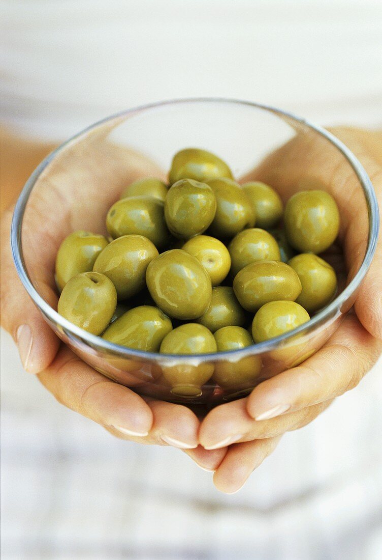 Hands holding a bowl of green olives