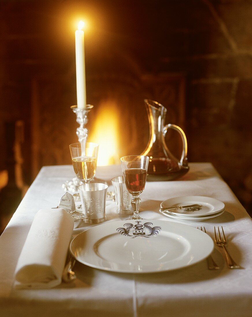 An elegant place-setting with wine, candlelight & open fire