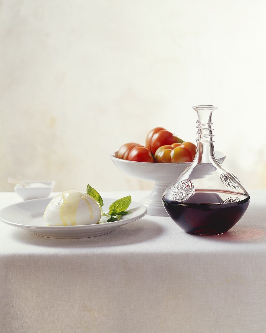 Still life with mozzarella, tomatoes and carafe of red wine