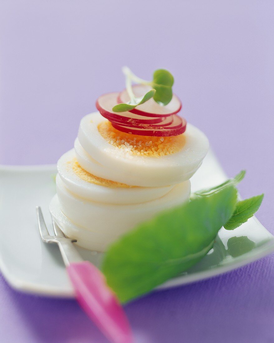 A sliced boiled egg, stacked on a plate