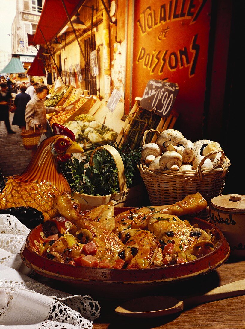 Coq au vin mit Zutaten, im Hintergrund französischer Markt