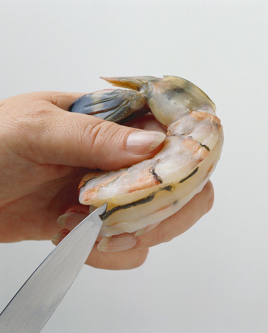 Deveining a raw prawn with a knife