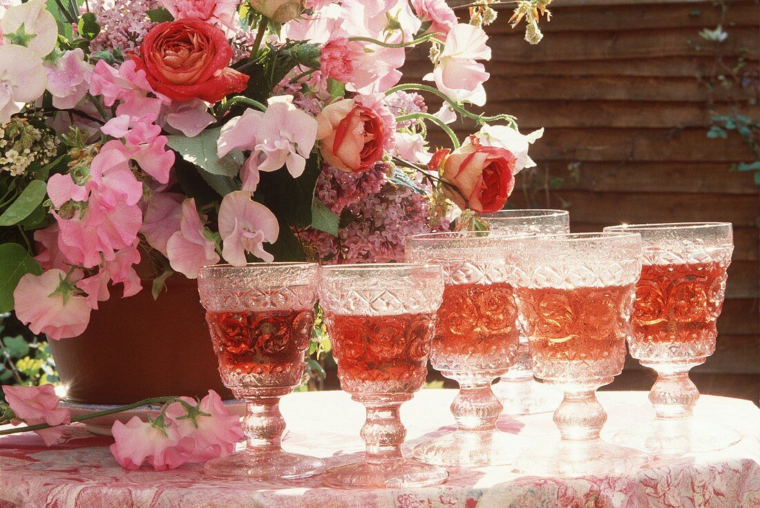 Several glasses of rosé wine with a vase of flowers
