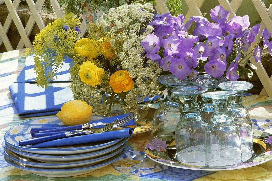 Tisch mit Geschirr, Besteck und Blumendeko im Freien