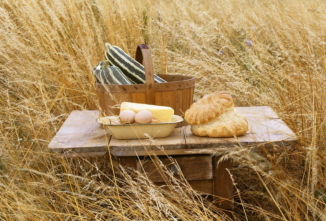 Bread, eggs, cheese, marrows on a small table in a cornfield