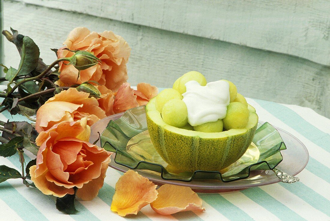 Melon balls and cream in hollowed-out melon, roses