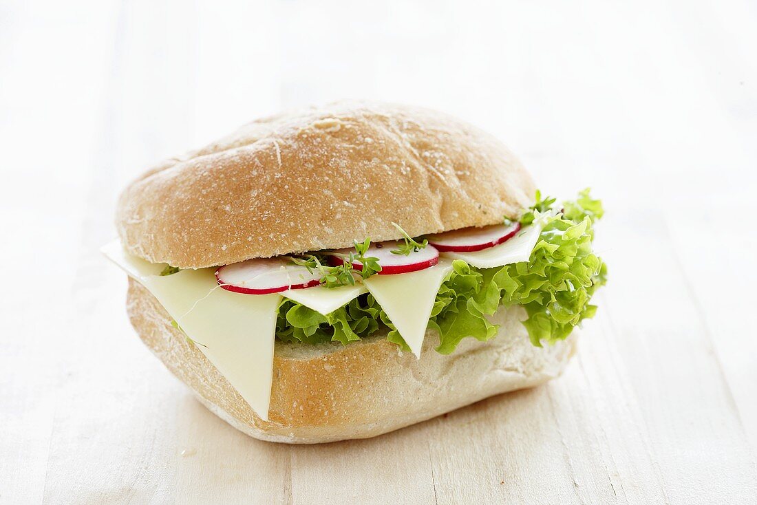 A bread roll filled with cheese, radishes and cress