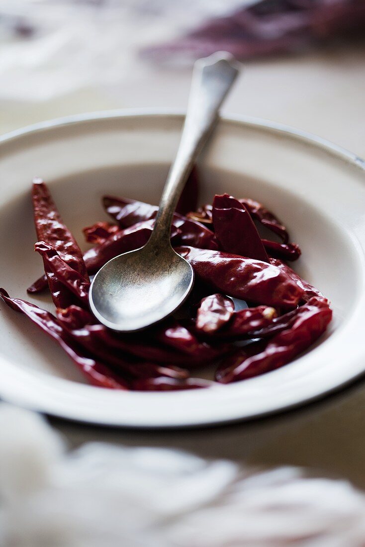 A plate of dried red chili peppers with a spoon