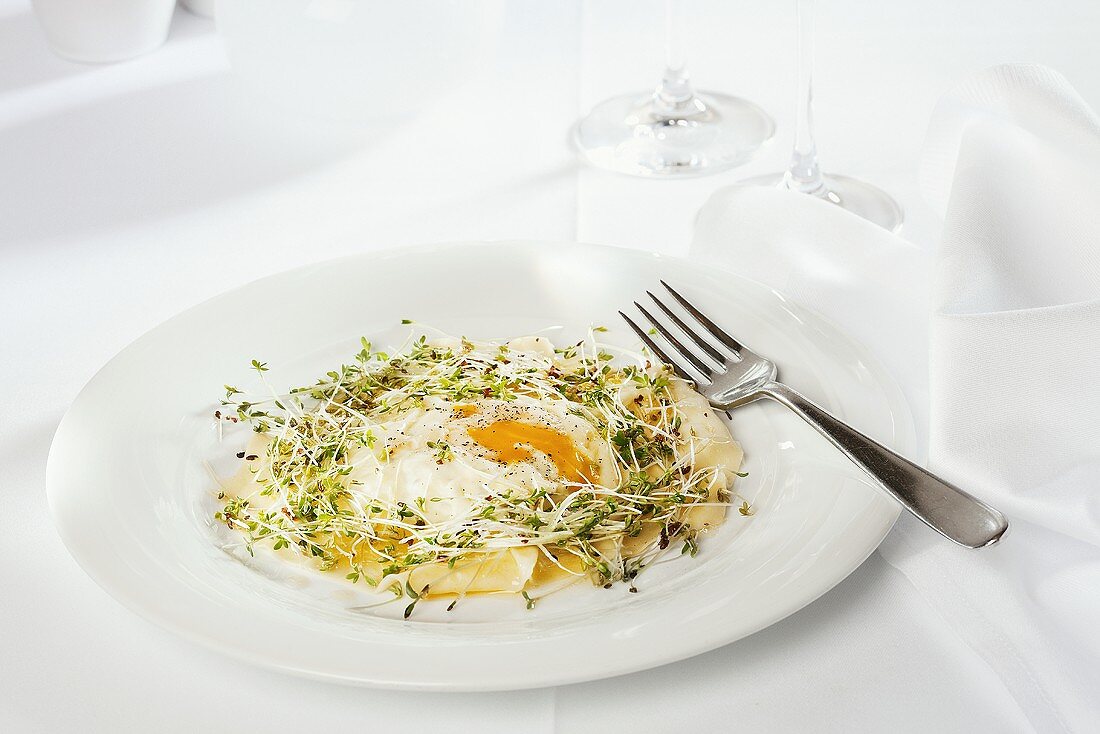 Giant ravioli with egg in a nest of herbs