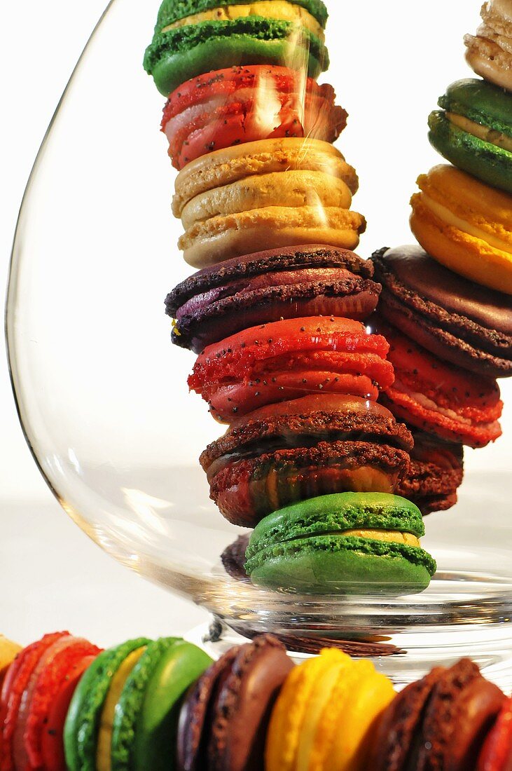 A stack of colourful macaroons in and in front of a glass