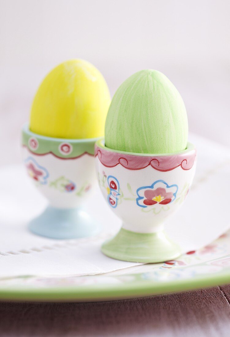 Two cooked, coloured eggs in egg cups