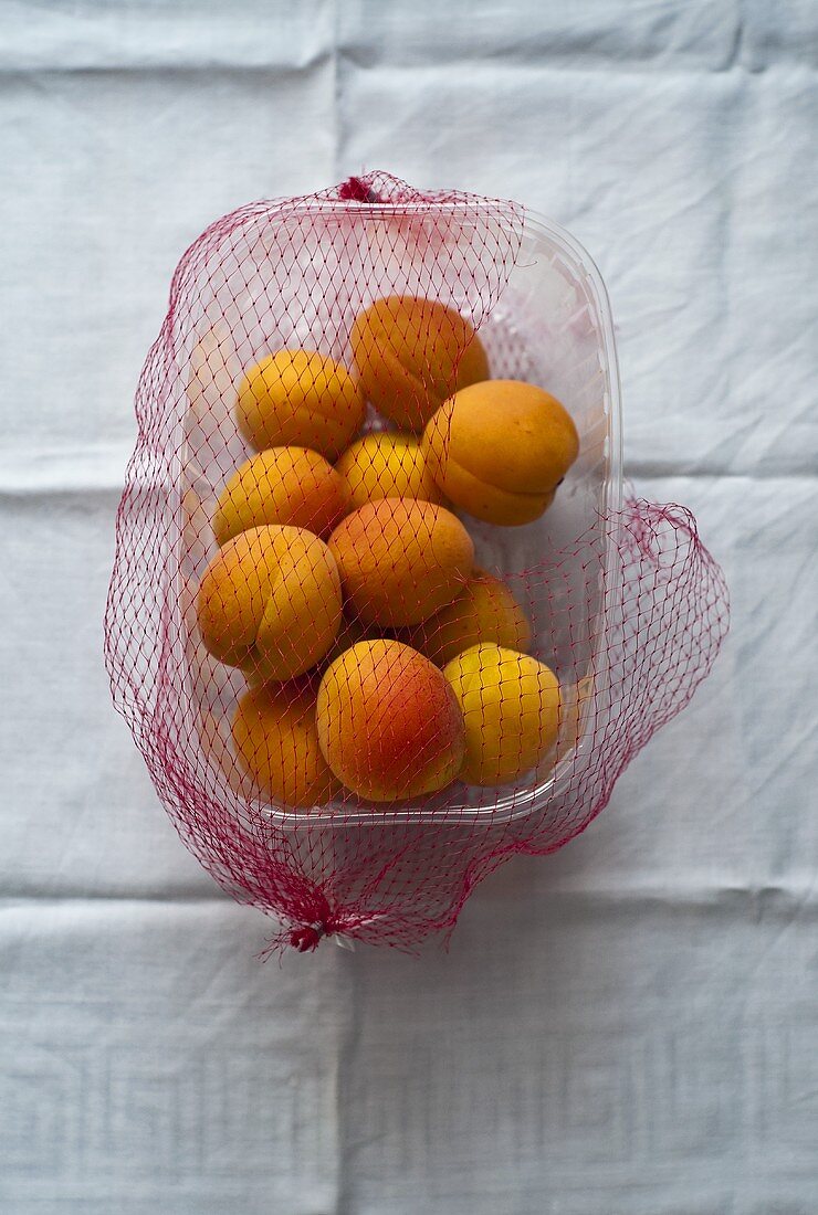 Aprikosen in Plastikschale mit Netz