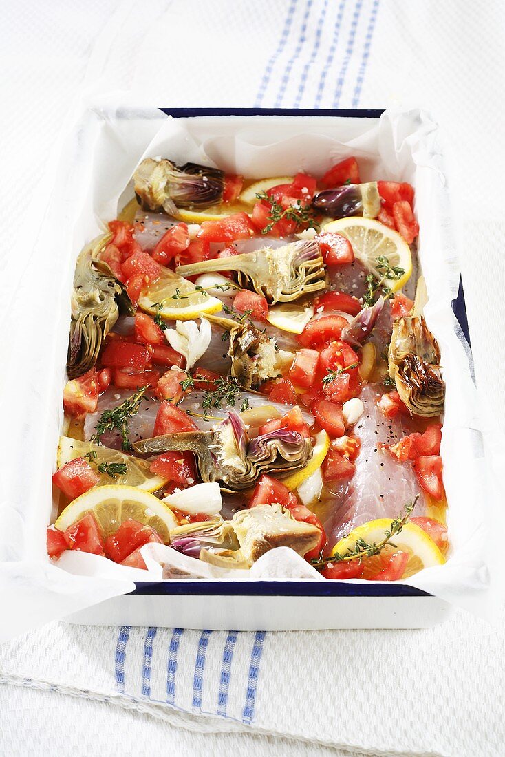 A fish bake with artichokes, tomatoes and lemons (raw)