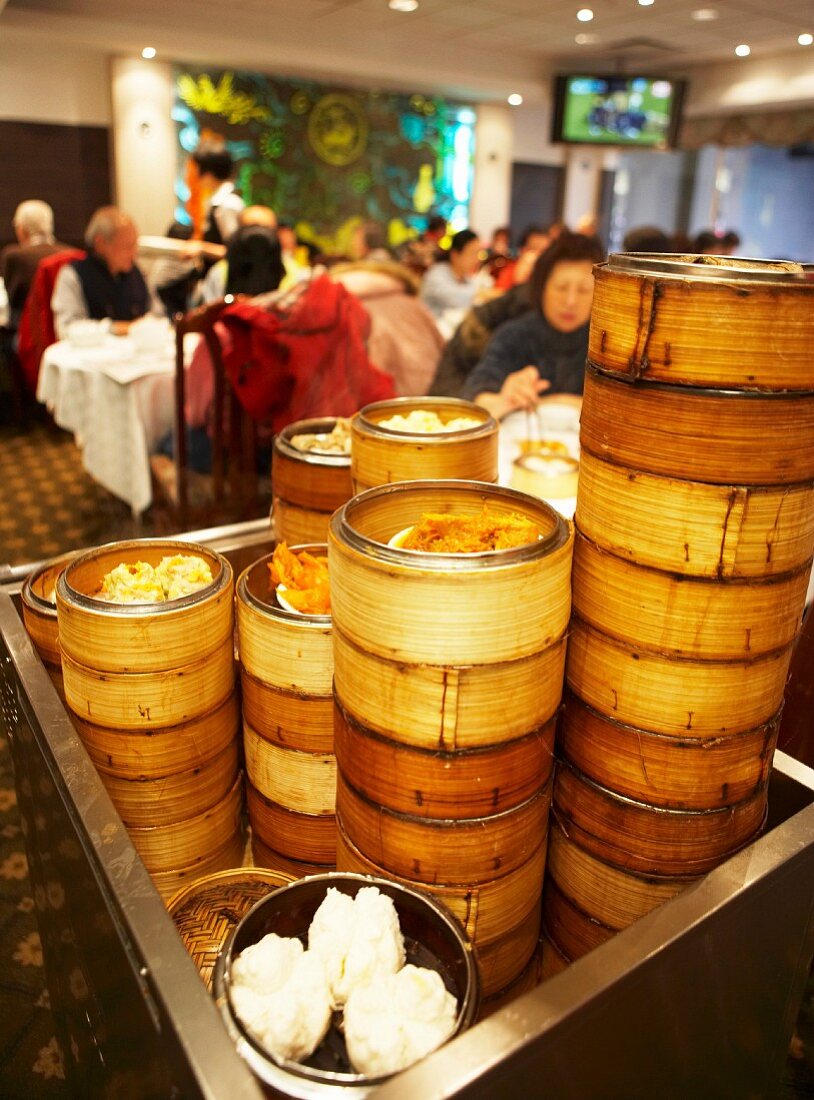 Lots of bamboo steamers filled with dim sum on a trolley in a Chinese restaurant