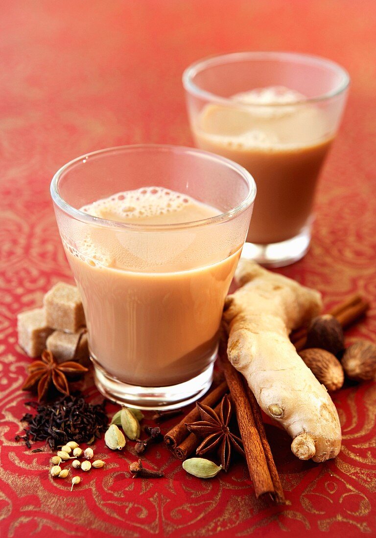 Two glasses of chai tea with spices and sugar cubes