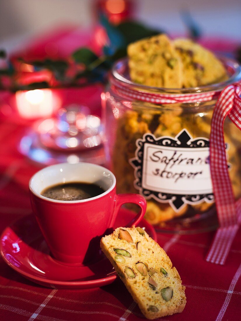 Pistachio and saffron biscuits in a cookie jar with a cup of espresso