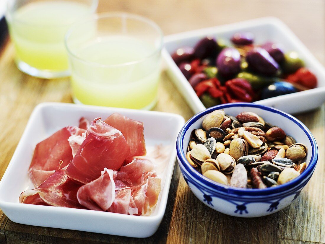 Glasses of absinth with ham, olives and nuts