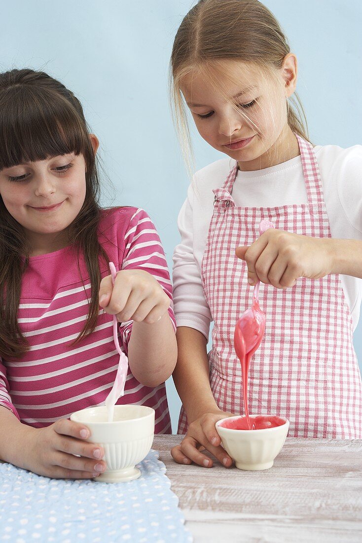 Zwei Mädchen bereiten Zuckerglasur zu
