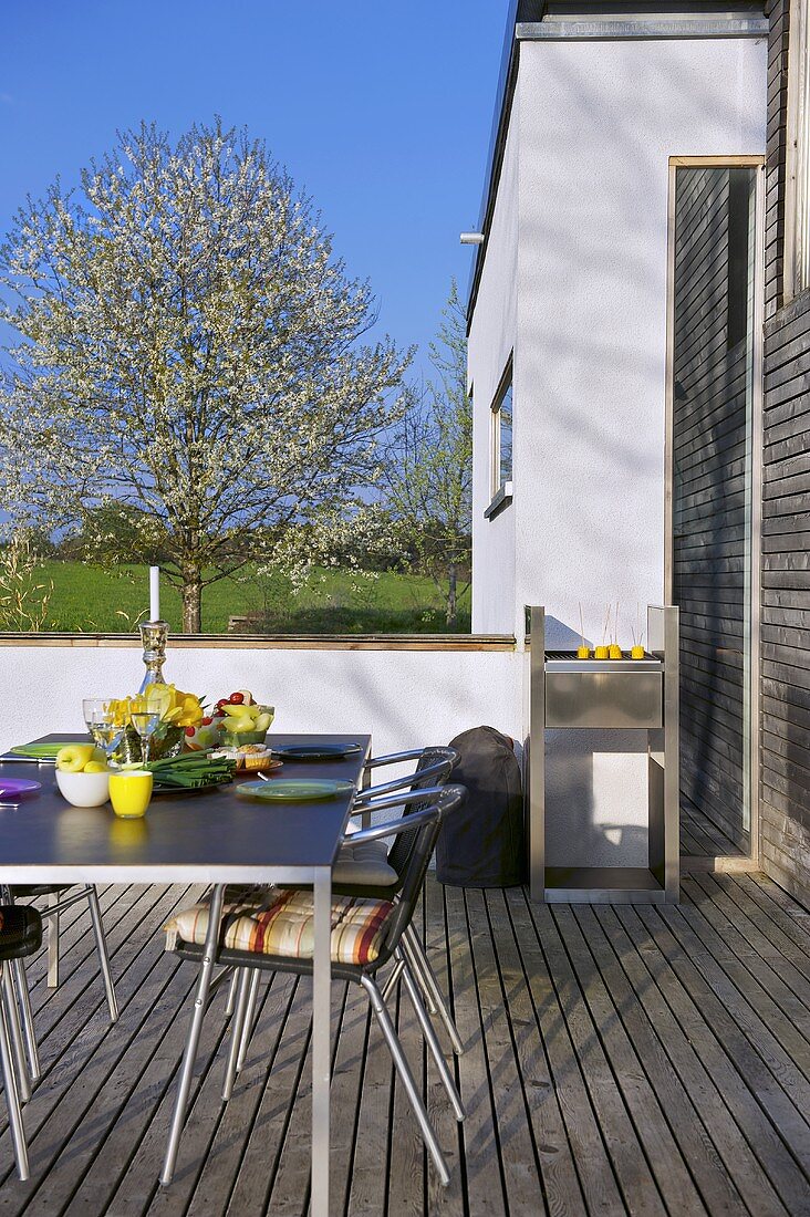 A table laid on a terrace with a barbeque