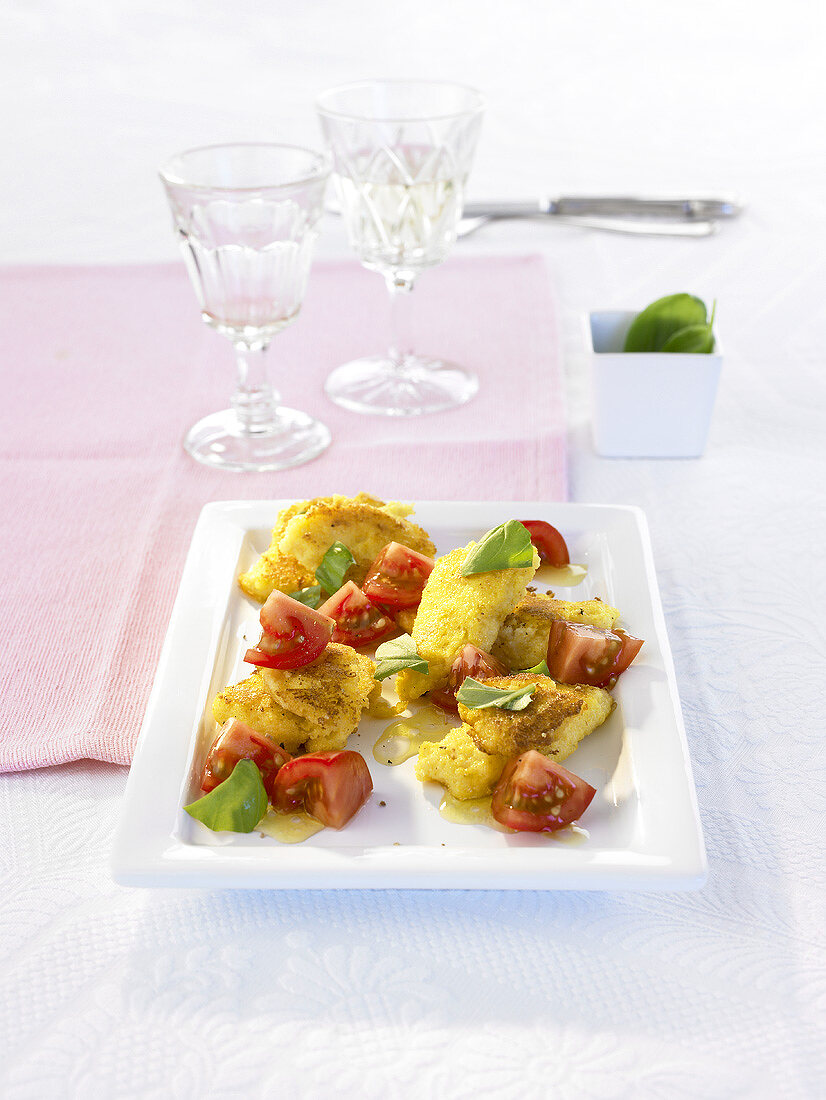 Fried polenta with tomatoes and basil on a platter