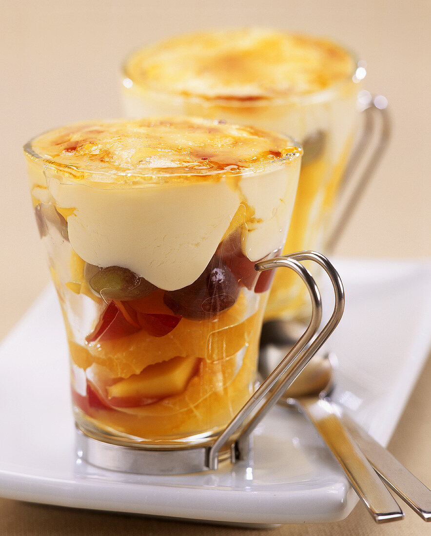 Fruit salad with vanilla cream in glass cups, caramelised