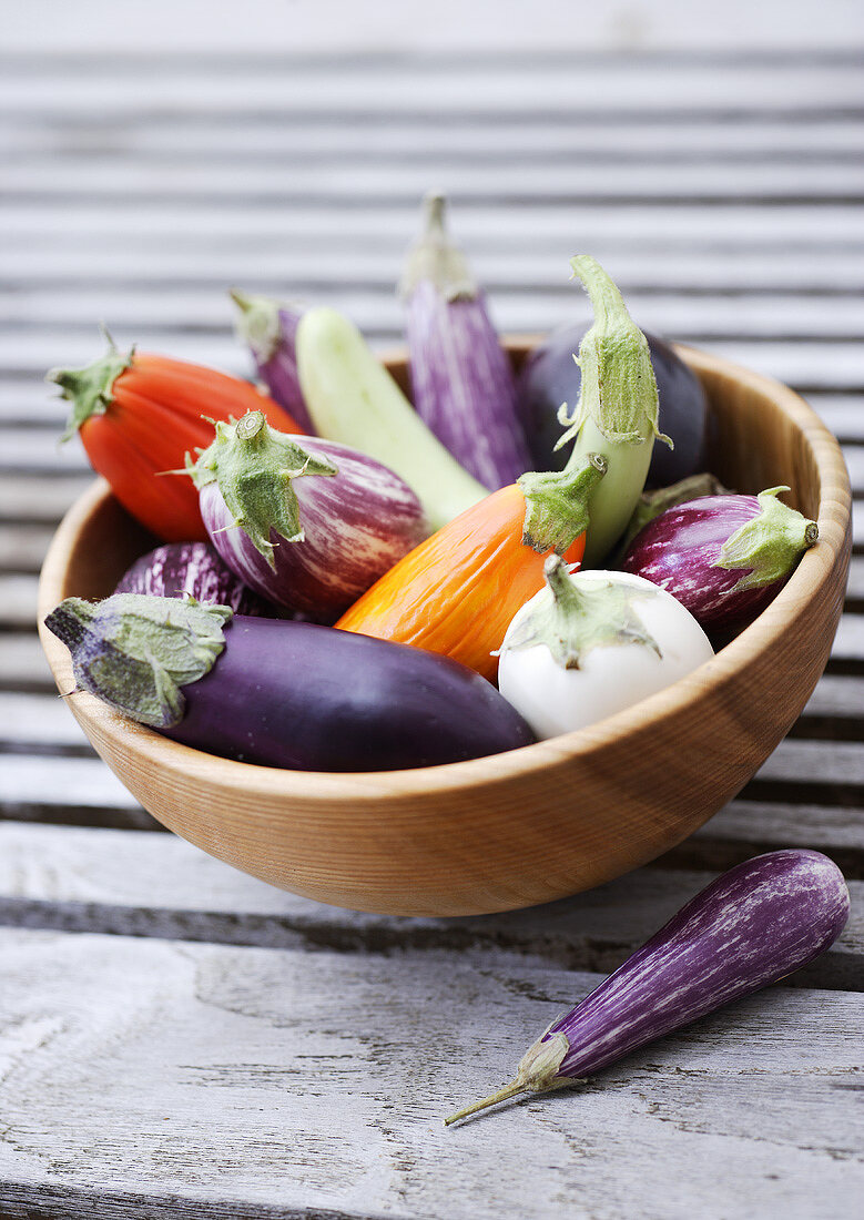 Various types of aubergines in a wooden bowl