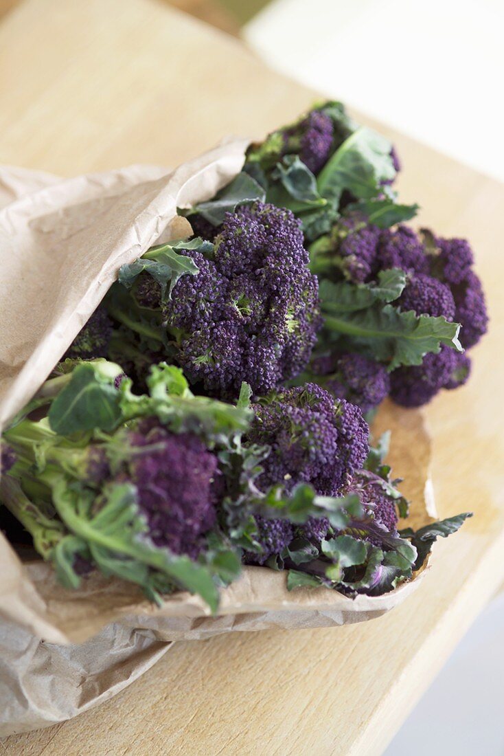 Violetter Brokkoli mit Blättern in einer Papiertüte verepackt
