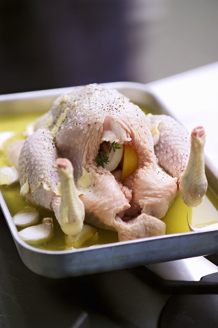 Oven-ready chicken in a deep roasting tin with garlic
