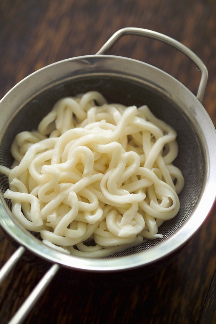 Cooked udon noodles in a sieve