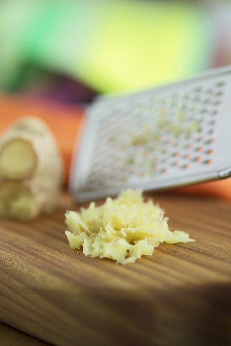 Grated ginger with a grater on a wooden board