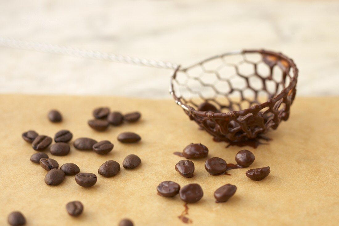 Mit Schokolade überzogenene Kaffeebohnen und Sieb