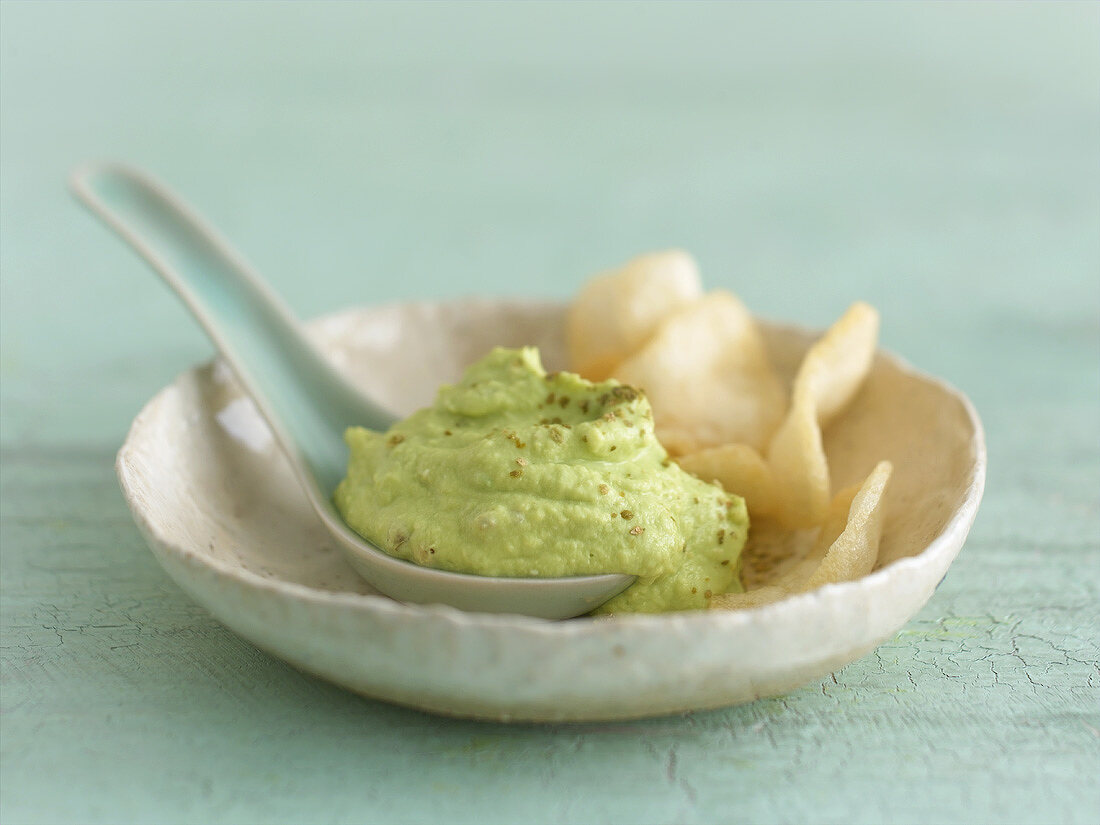 Avocado and wasabi dip with spoon in a porcelain dish