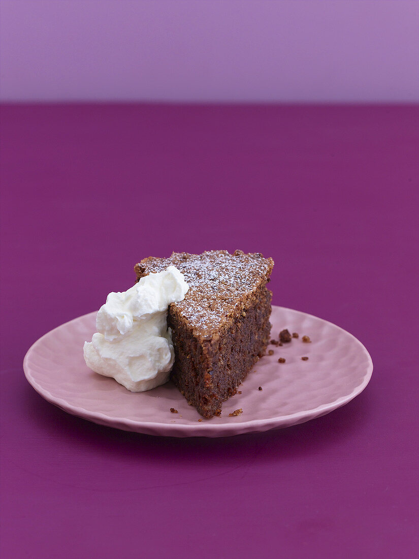 A piece of chocolate almond cake with whipped cream
