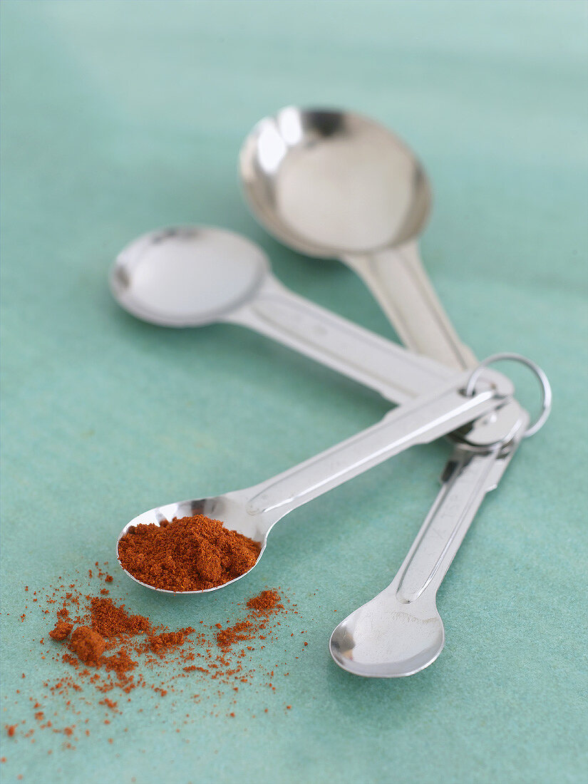 Paprika powder on one of four measuring spoons
