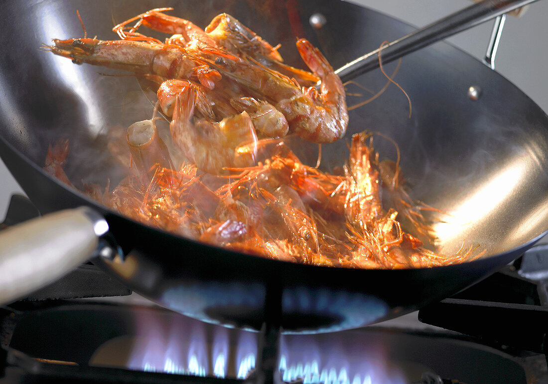 Gambas braten im Wok über einer Gasflamme